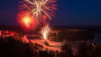 Au-dessus des chutes du Rhin, un grand feu d'artifice rouge illumine le ciel.