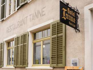Sapin de Schaffhouse Sur la façade d'une maison, on peut lire en gros "Restaurant Tanne". Il a des volets verts et une enseigne noire en fer avec des lettres dorées "Hotel Tanne".