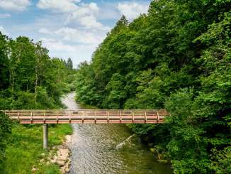 Pont de Wutach Schleitheim Un pont en bois au-dessus d'une rivière. A gauche et à droite, une forêt.
