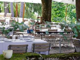 Garderie de Bad OSterfingen Des tables nappées de blanc et des chaises en bois sont installées dans un restaurant de jardin sous les marronniers.