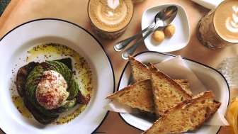 Auf dem Tisch steht getoastetes Brot, Ein Toast mit Avocado und Ei und zwei Kaffees