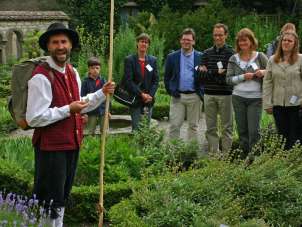 Délicieux Schaffhouse Visite guidée du jardin d'herbes aromatiques Une personne habillée en costume d'époque, un bâton en bois à la main, et un groupe de 7 personnes se tiennent dans un jardin d'herbes aromatiques. Le groupe écoute attentivement la personne déguisée.
