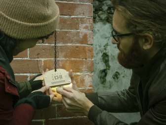 Code de Sato Deux personnes tentent de crocheter une serrure spéciale sur une escape room à l'extérieur.