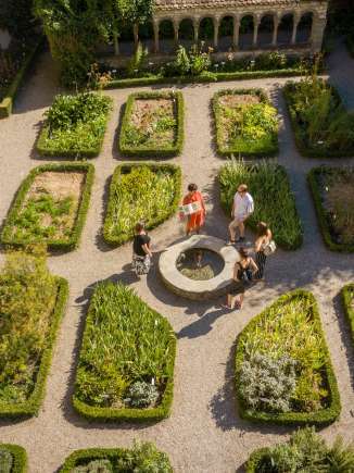 Visite guidée de la ville de Schaffhouse Un groupe se tient autour d'une petite fontaine dans le jardin d'herbes aromatiques de Schaffhouse. Une femme en dit plus sur l'histoire.
