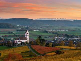Ambiance du soir à Hallau avec église Vue sur les vignes dorées et l'église St. Moritz à Hallau. Le ciel est teinté de rouge et d'orange.