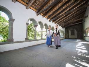 Chemin des Huguenots Cloître de Schaffhouse Deux femmes déguisées en huguenots se promènent dans le cloître de Schaffhouse. L'une porte un tablier bleu et l'autre un tablier violet.