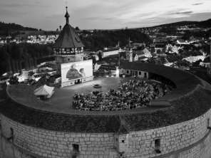 Vue d'en haut sur une forteresse ronde. Sur le créneau se trouve un grand écran devant lequel sont assis les spectateurs de cinéma.