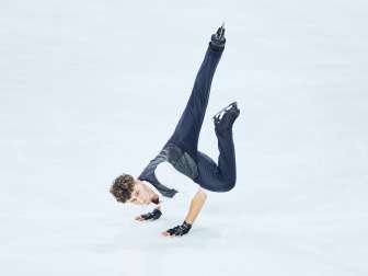 Lukas Britschgi, patineur artistique, prend la pose sur la glace. Il se tient sur ses deux mains.