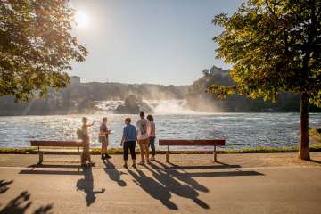 Un groupe avec un guide se tiennent devant les chutes du Rhin, la plus grande chute d'eau d'Europe.