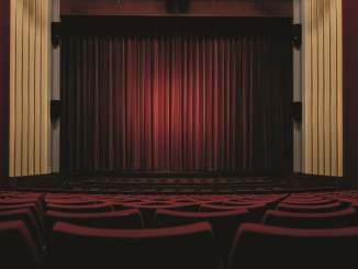Municipal theatre de Schaffhouse Rideau Une salle vide avec une scène. Toutes les chaises sont rembourrées de rouge. Le rideau tiré est également rouge.