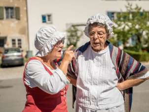 Deux maîtresses vêtues d'une robe et d'un bonnet blanc "papotent" ensemble.