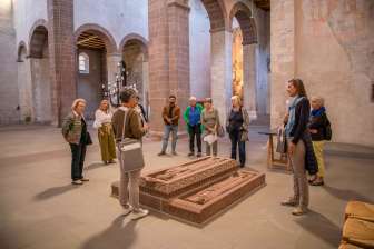 Un groupe avec un guide se tient autour de plaques funéraires dans une église.