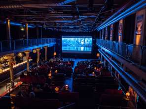Festival du film de Schaffhouse Une salle de spectacle a été transformée en cinéma. Différentes chaises et fauteuils en tissu y sont installés et un grand écran est suspendu tout devant.