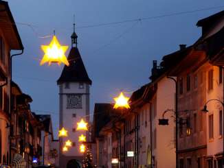 Marché de l'Avent à Neunkrich Des étoiles lumineuses sont suspendues au-dessus d'une ruelle à Neunkirch. En arrière-plan, on aperçoit une tour.