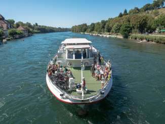 Das Kursschiff mit Gästen fährt auf dem Rhein vorbei an Diessenhofen.