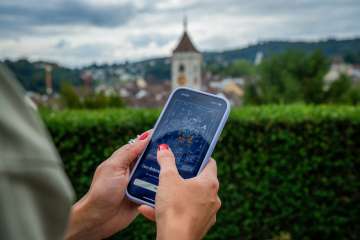 Une main tient un téléphone portable. On y voit l'énigme numérique Foxtrail GO.
