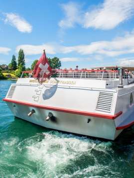 Vue de l'arrière d'un bateau blanc arborant un drapeau suisse.