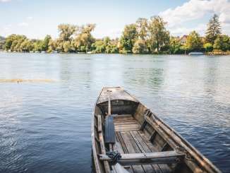 Un bateau traditionnel en bois de Schaffhouse est amarré à la rive. On y voit le Rhin et la rive verdoyante du Rhin.