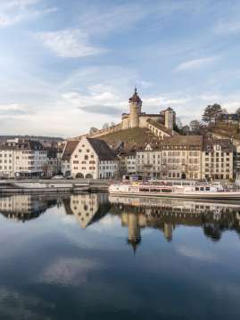 Vue depuis le Rhin limpide sur la vieille ville hivernale avec le bateau et le Munot.