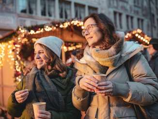 Deux femmes, un gobelet de vin chaud à la main, sur un marché de Noël.