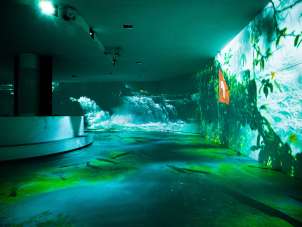 Programme Rhyality Rhienfall Une salle équipée de divers projecteurs. Des images d'eau sont projetées sur les murs.