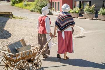 Wöschwiiber Visite guidée de Wilchingen Deux "Wöschwiiber" traversent le village avec un chariot à échelle en bois. Ils portent une cagoule blanche.