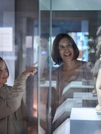 Une mère et son enfant sont dans un musée et regardent des sculptures.