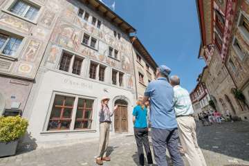 Visite guidée de la ville de Stein am Rhein Un groupe se tient devant une maison avec des peintures sur la façade. Un guide en dit plus.