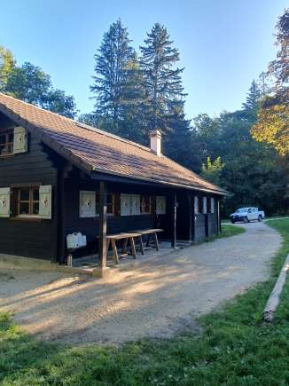 Une cabane en bois se trouve dans une prairie entourée de forêt.