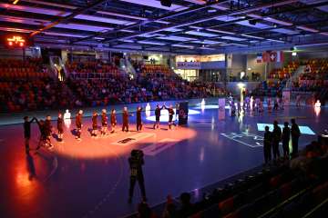 Les joueurs d'une équipe de handball se tiennent au milieu de la salle et applaudissent l'équipe adverse.