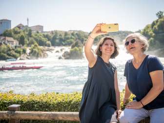 Amies au bord de la chute du Rhin Deux amies prennent un selfie avec les chutes du Rhin, la plus grande chute d'eau d'Europe, en arrière-plan.