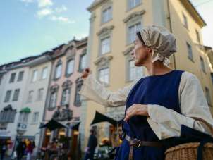 Krämerin Schaffhausen Visite guidée La personne déguisée en épicière pointe son bras vers un site touristique.