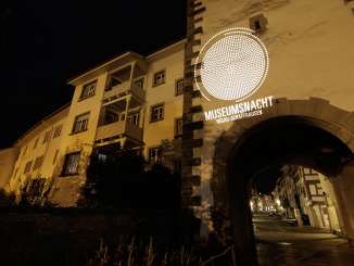 Nuit des musées Hegau-Schaffhouse Une ancienne façade de la ville avec un arc de porte dans la nuit. La façade est illuminée avec le slogan "Museumsnacht Hegau-Schaffhausen.