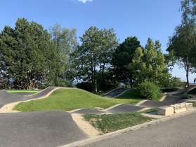 Une pumptrack est entourée d'arbres.