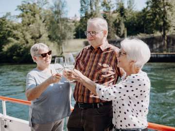 Trois personnes âgées dégustent du vin sur la navigation à horaire régulier sur le Rhin entre Schaffhouse et Stein am Rhein.