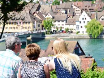 Visite guidée de la ville de Stein am Rhein Trois personnes regardent attentivement un plan. En arrière-plan, on voit le Rhin et la vieille ville de Stein.