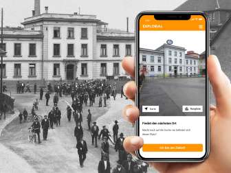 Explorial Neuhausen am Rheinfall Une main tient un téléphone portable devant une image en noir et blanc. Sur le téléphone portable, on voit le bâtiment tel qu'il est aujourd'hui.