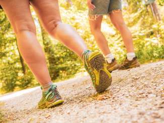 Deux personnes, chaussées de chaussures de randonnée, marchent sur un sentier naturel.