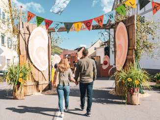 Un couple se tient la main. Ils se promènent dans les ruelles décorées de couleurs vives lors de la fête d'automne de Wilchingen.