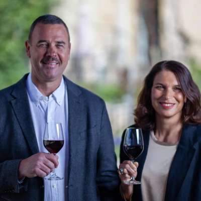 Portrait Markus und Katrin Hedinger. Beide halten ein Glas Rotwein in der Hand.