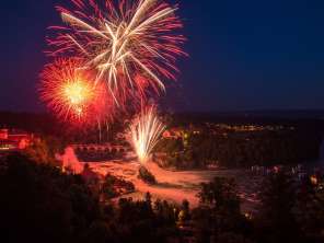 Au-dessus des chutes du Rhin, un grand feu d'artifice rouge illumine le ciel.