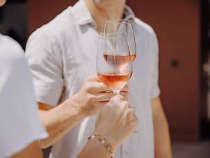 Deux personnes trinquent avec un verre de rosé.