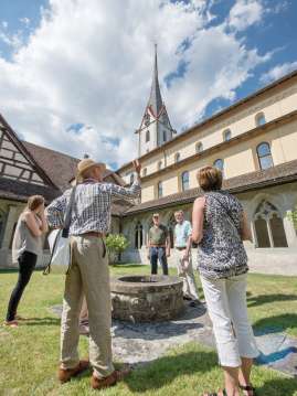 Visite guidée de la ville de Stein am Rhein Un groupe avec guide se tient dans la cour intérieure d'un cloître autour d'une petite fontaine.