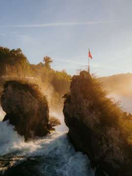 Les chutes du Rhin en automne Vue de derrière sur les deux rochers au milieu de la cascade. La lumière de Goldie brille sur la cascade.
