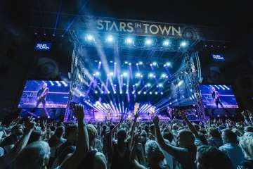 Stars in Town Schaffhouse Concert avec une grande scène et beaucoup de public ainsi que des projecteurs avec une lumière bleue.